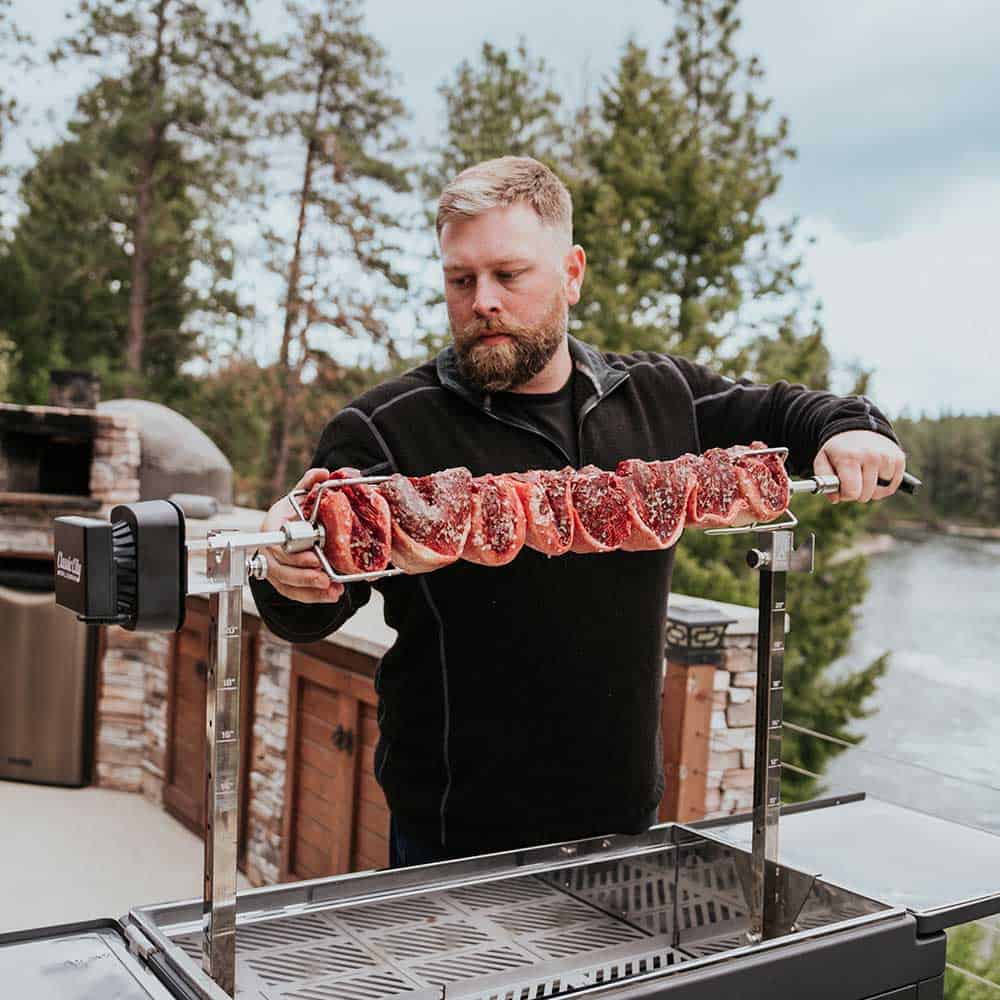 Derek Wolf using the rotisserie attachment on the FYR Grill to cook beef at a high level