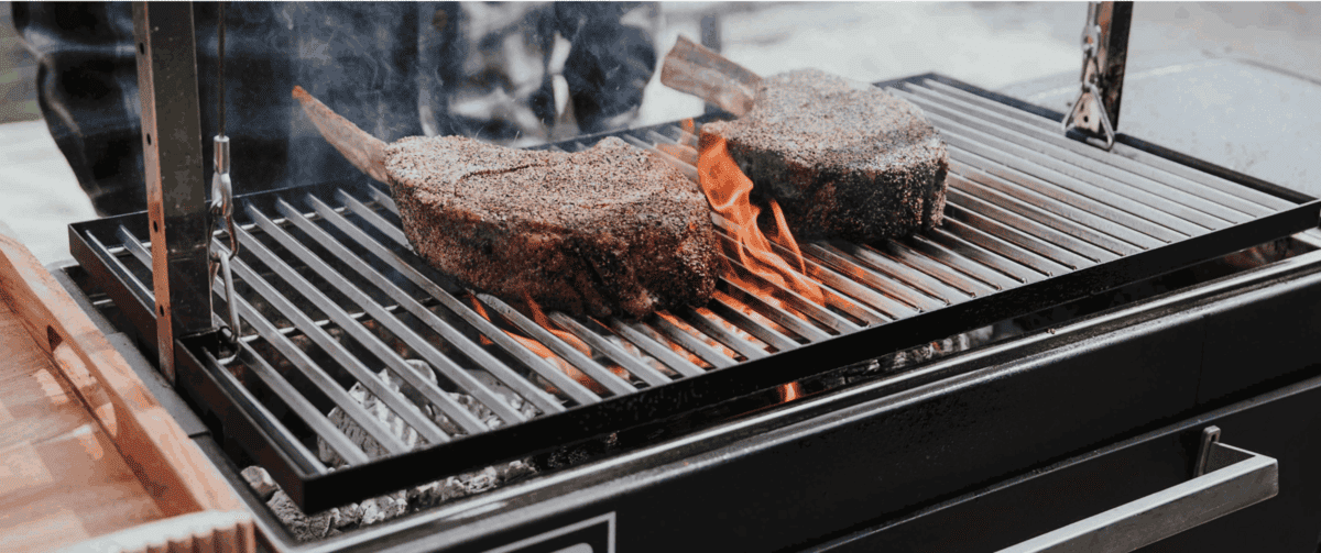 Two steaks cooking on FYR Grill's Santa Maria attachment