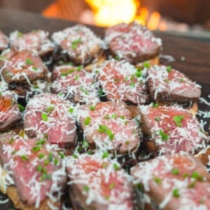 The French Onion Steak Crostini are assembled, sprinkled with garnish, and ready to serve.