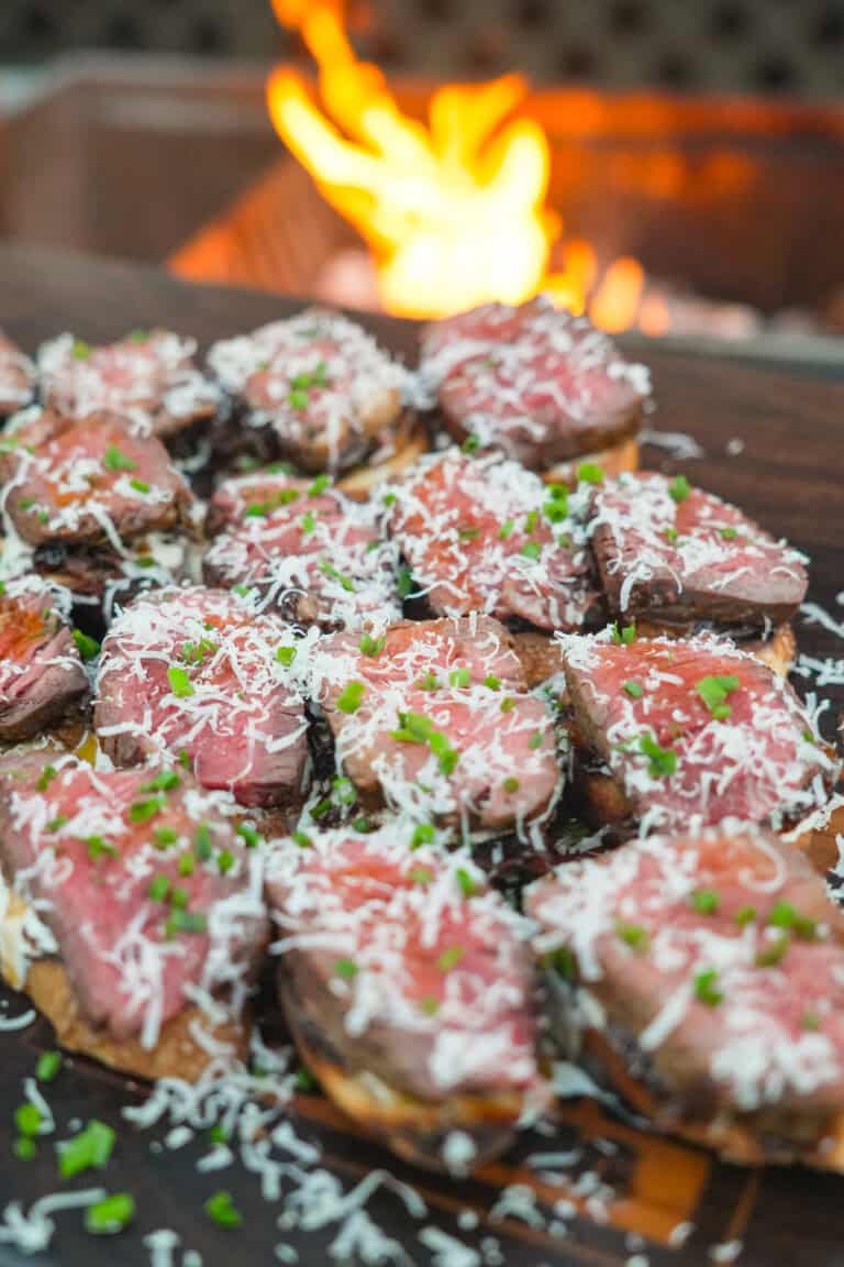 The French Onion Steak Crostini are assembled, sprinkled with garnish, and ready to serve.