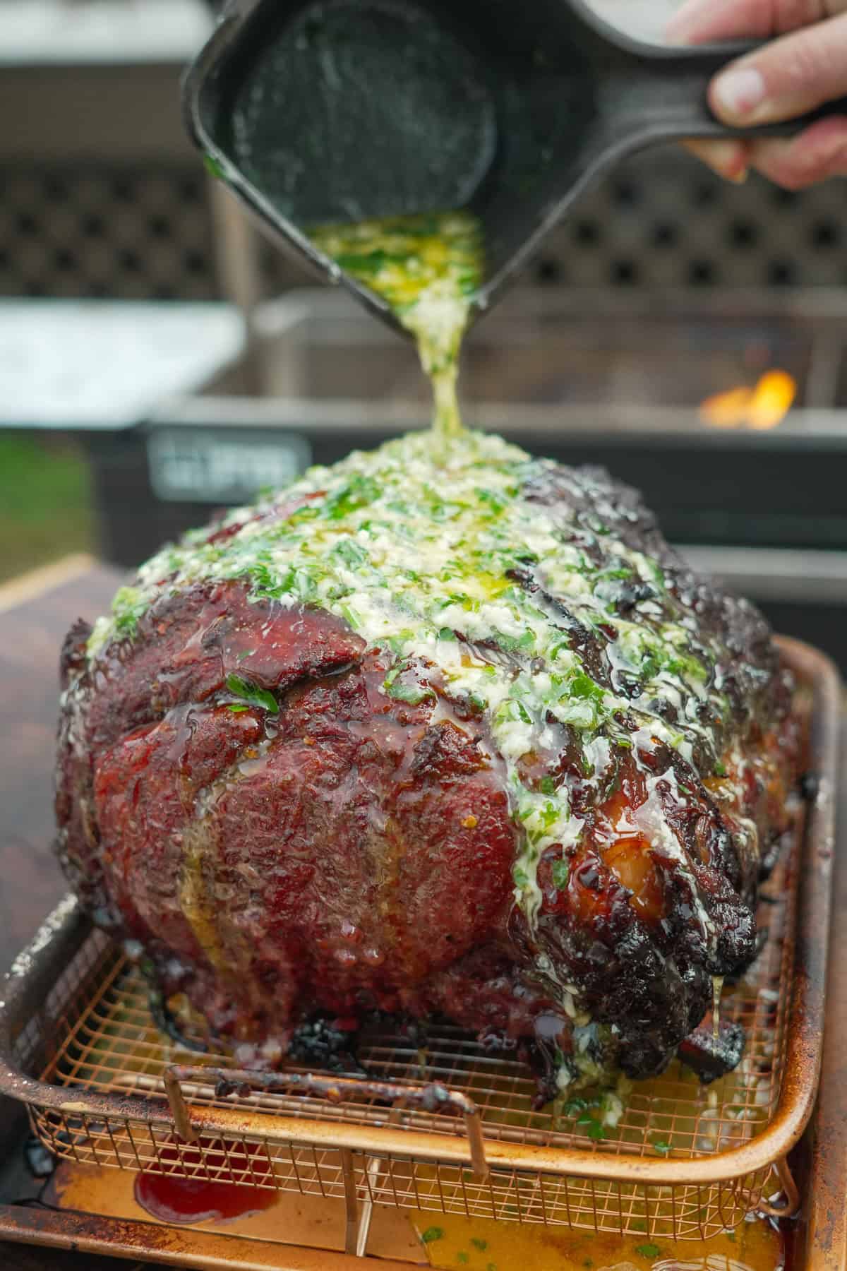 Pouring herb butter over the cooked hot honey smoked prime rib