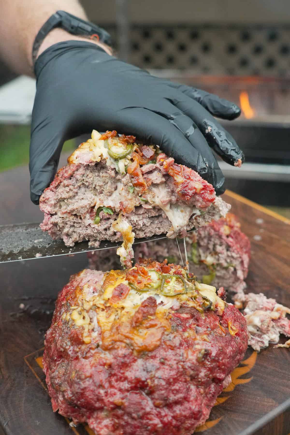Cutting open a slice of Texas Twinkie meatloaf to show the ingredients — cheese, brisket, bacon bits and jalapeños — stuffed inside