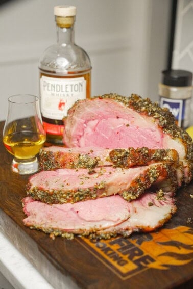 The perfectly cooked Whisky Injected Prime Rib is displayed on the cutting board in front of a bottle of Pendleton Whisky.