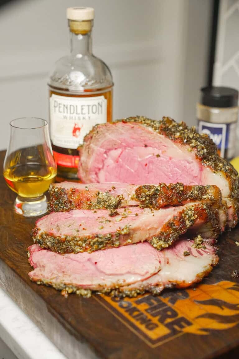 The perfectly cooked Whisky Injected Prime Rib is displayed on the cutting board in front of a bottle of Pendleton Whisky.