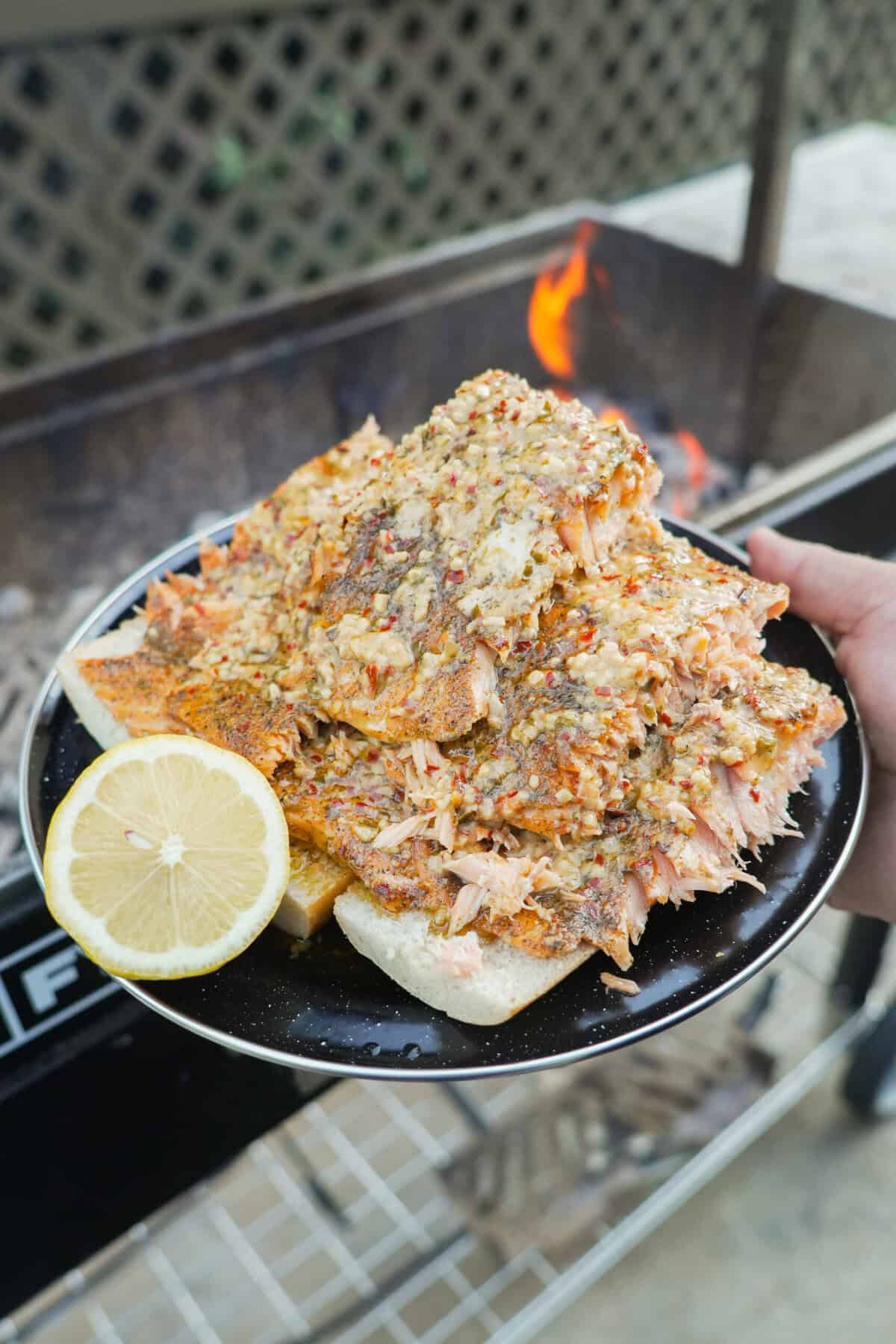 Grilled salmon fillets on a plate with a half lemon on the side for drizzling