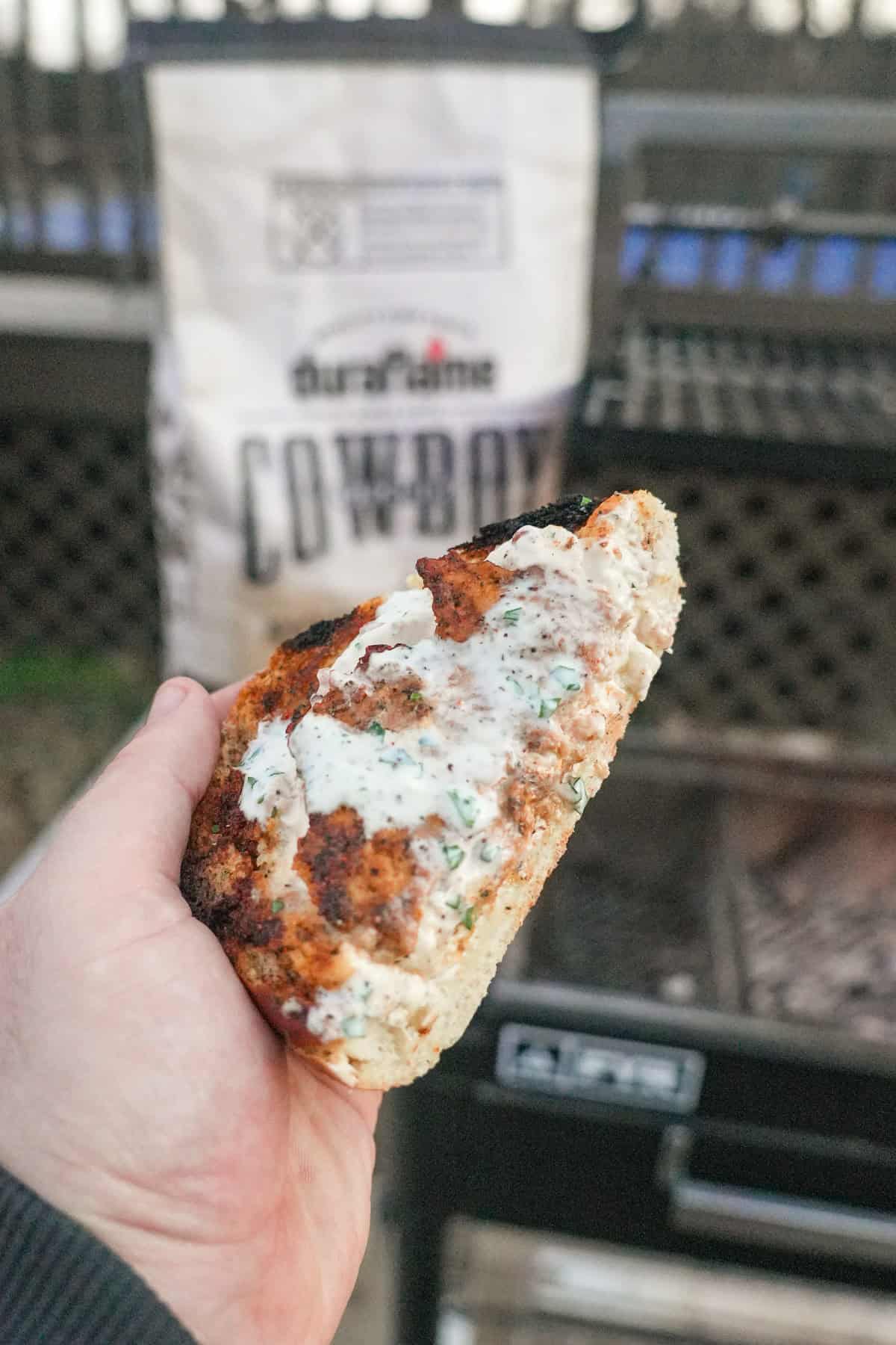 A close up of a sliced piece of chicken bacon ranch stuffed bread, with a bag of Cowboy Charcoal in the background