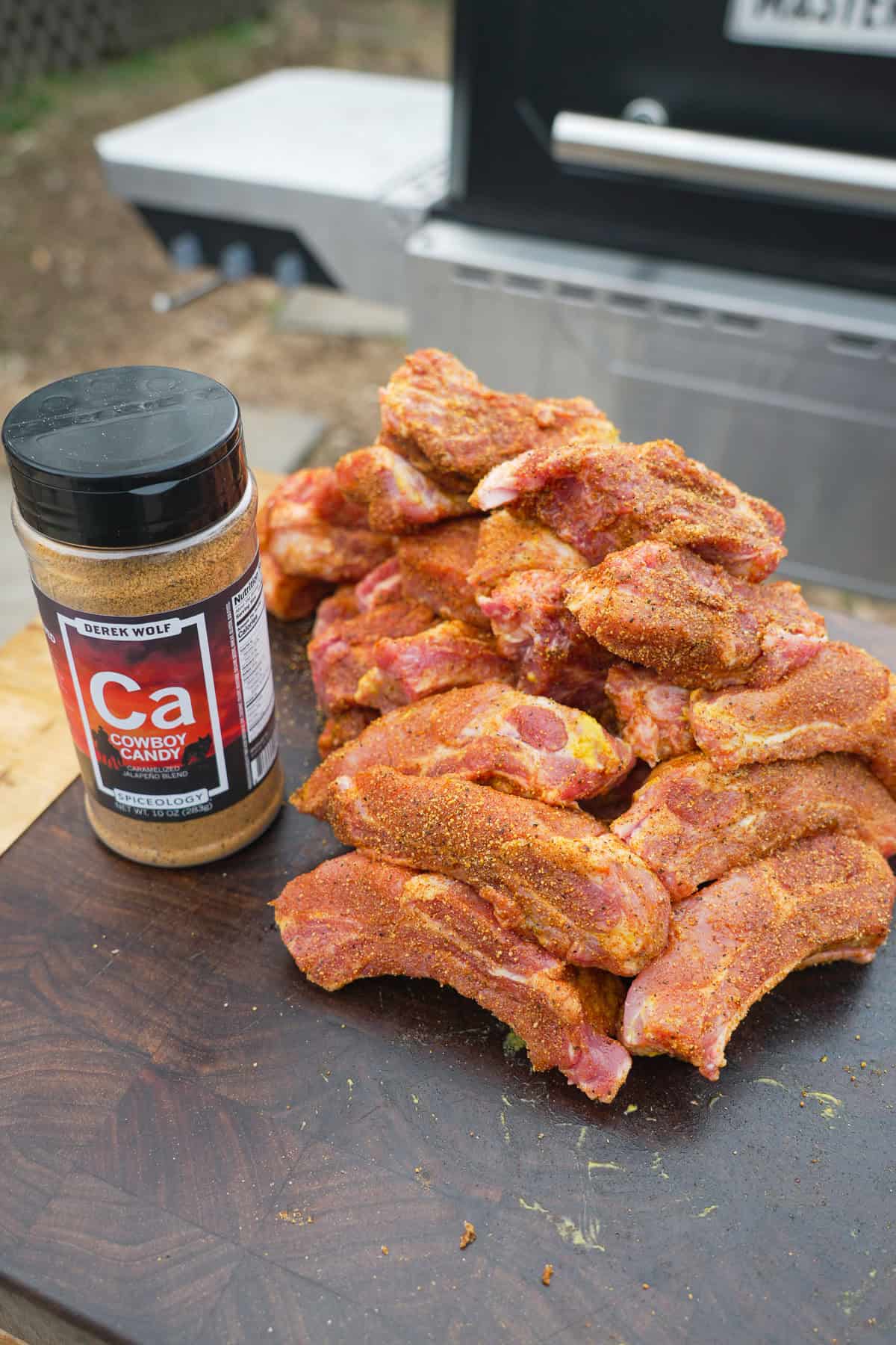 Individual ribs seasoned with Cowboy Candy Seasoning and a jar of the seasoning next to them