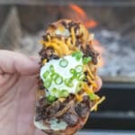 The Steak Fried Potato Skin is held up for a close-up in all its flavorful glory.