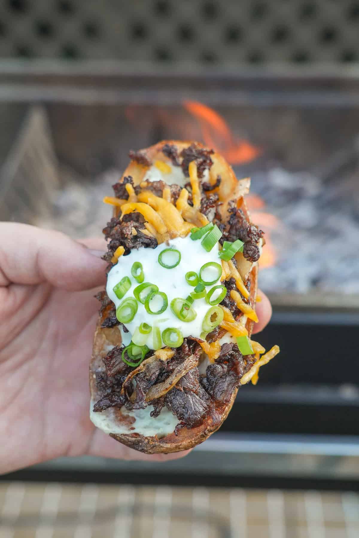 The Steak Fried Potato Skin is held up for a close-up in all its flavorful glory.