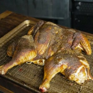 A whole cooked spatchcocked chicken laid out on a cutting board
