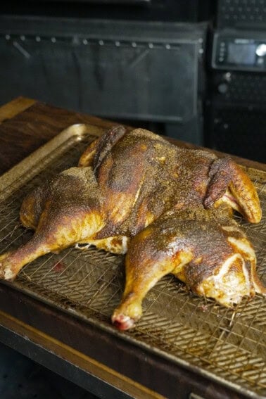 A whole cooked spatchcocked chicken laid out on a cutting board