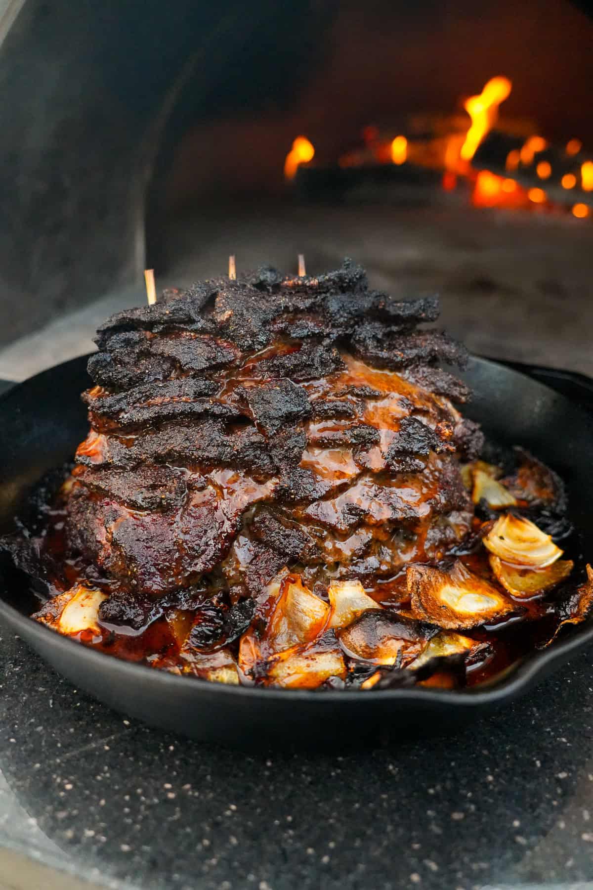 Cooked beef shawarma with wooden skewers holding the sirloin steak together and a bed of onions under