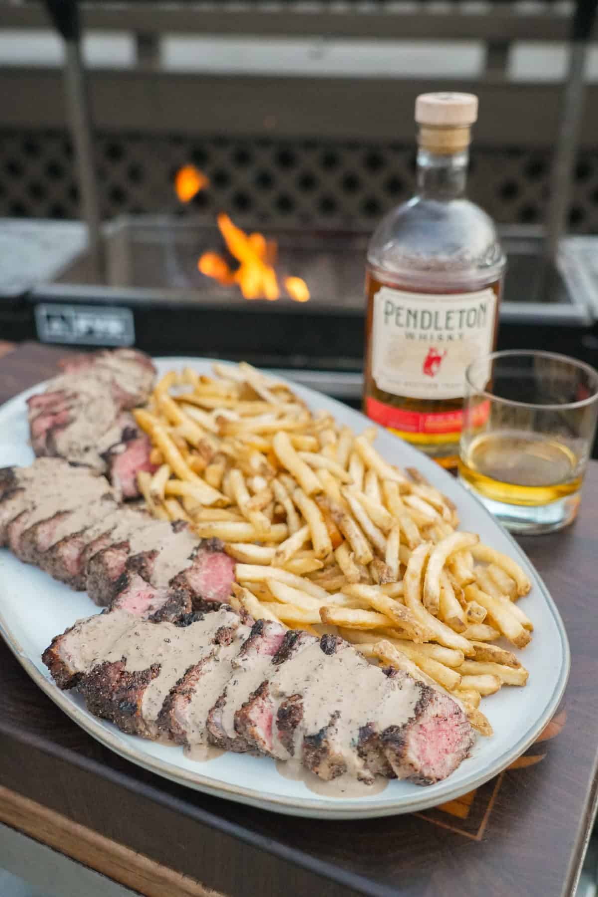 The full Steak au Poivre meal complete with the bottle of whisky and glass.
