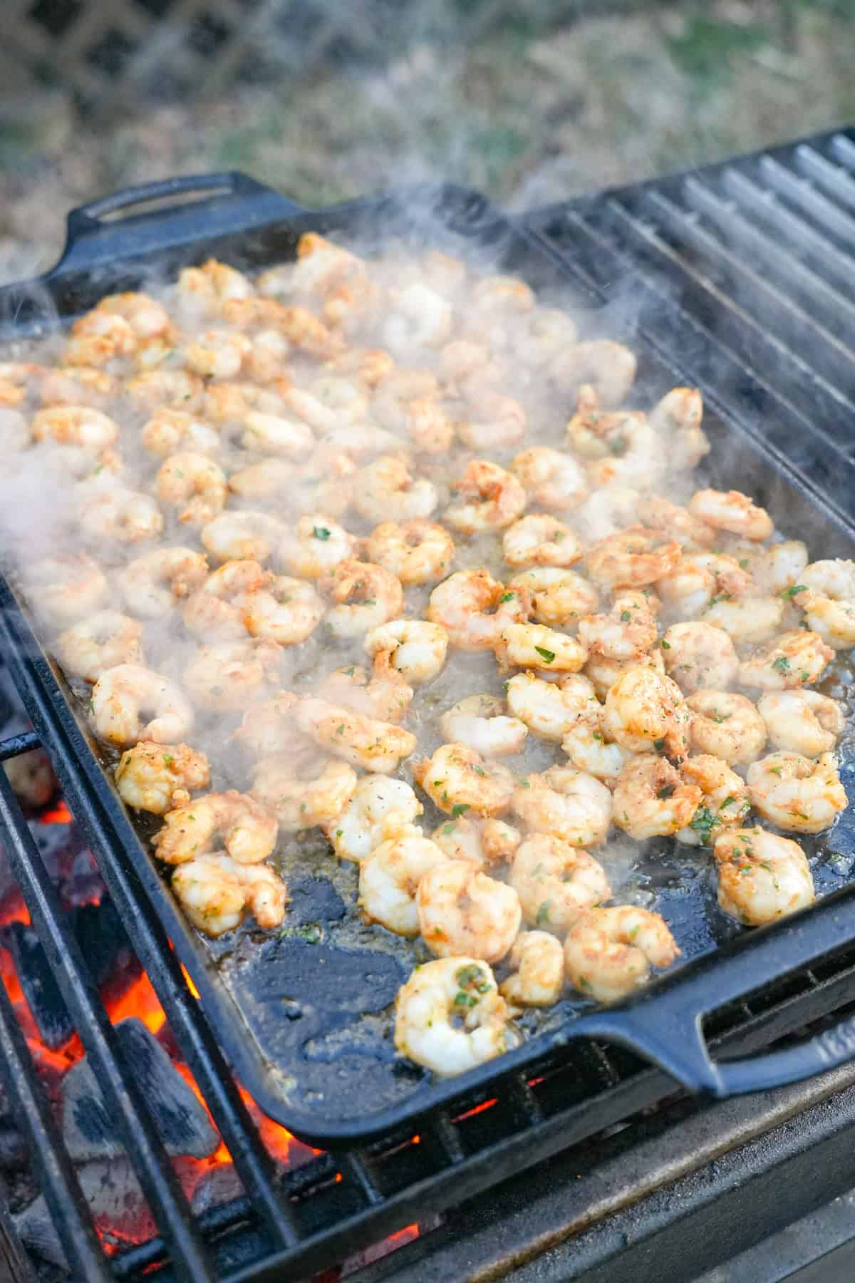 Cooking seasoned shrimp on a cast iron skillet on the grill