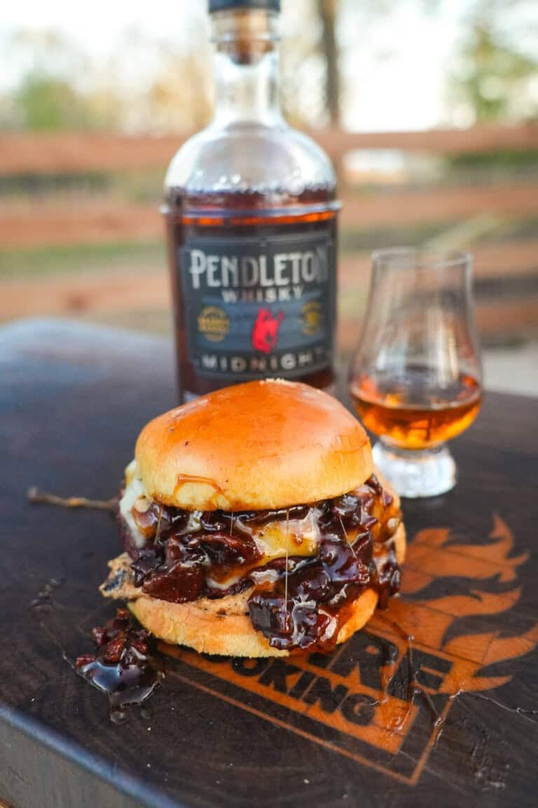 The Whiskey Jam Bacon Burgers recipe cover image features a burger in front of a bottle of whisky.