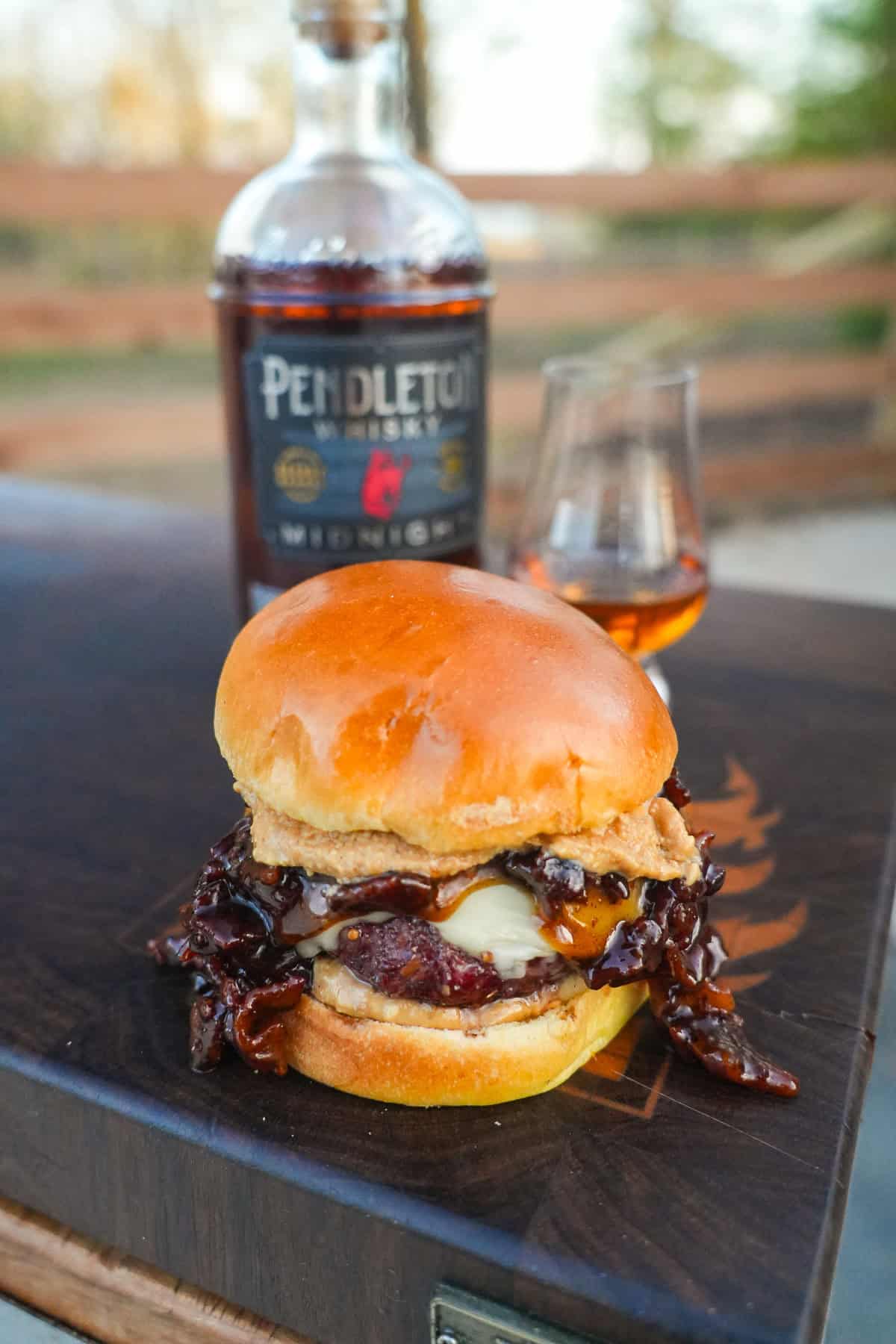 An extra shot of the Whiskey Jam Bacon Burgers in front of the Pendleton Whisky bottle.