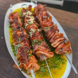 Grilled mortadella skewers atop a platter with Italian chimichurri