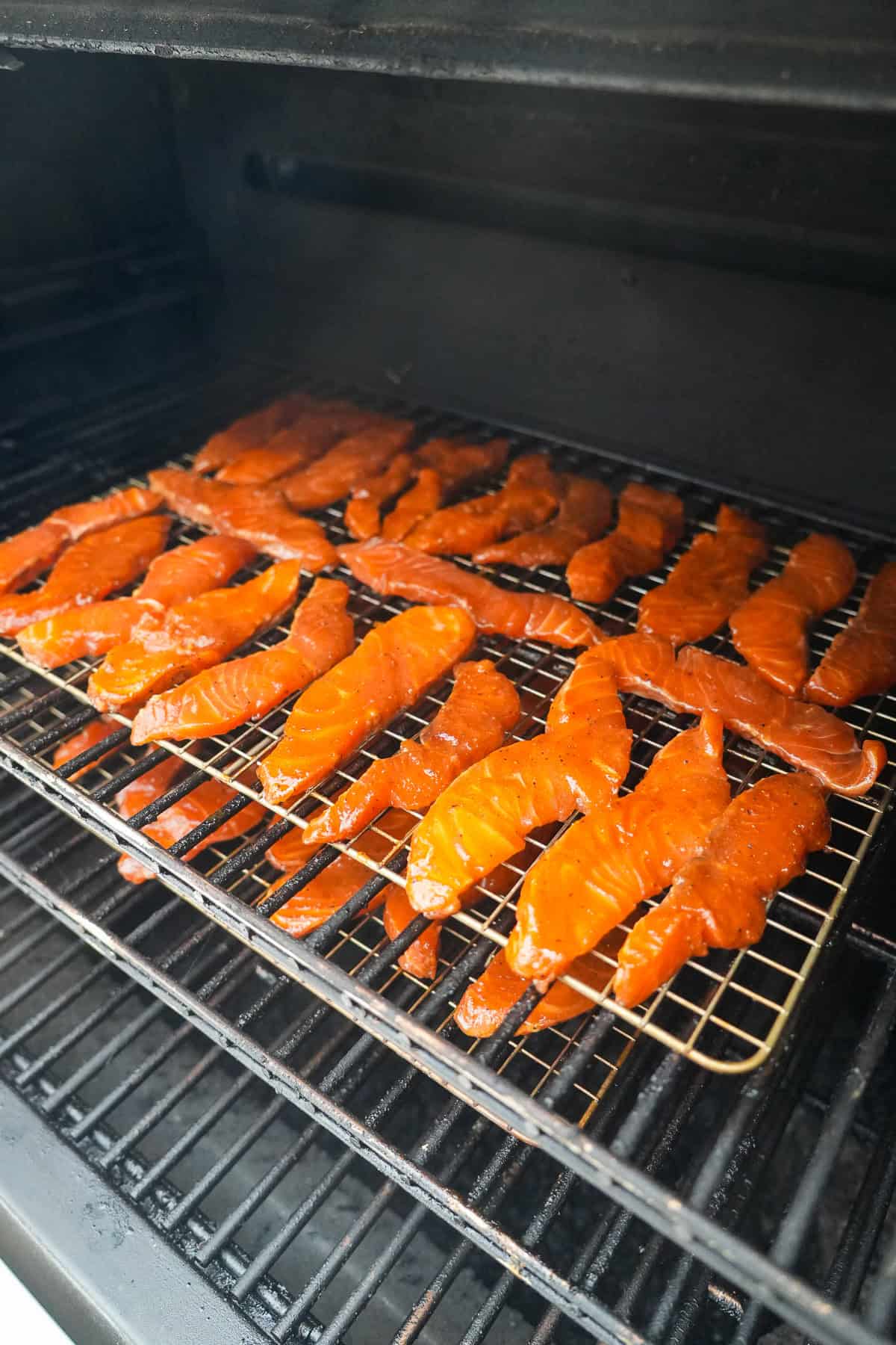 Each piece of fish is gently place on the smoker grill grates for even cooking.