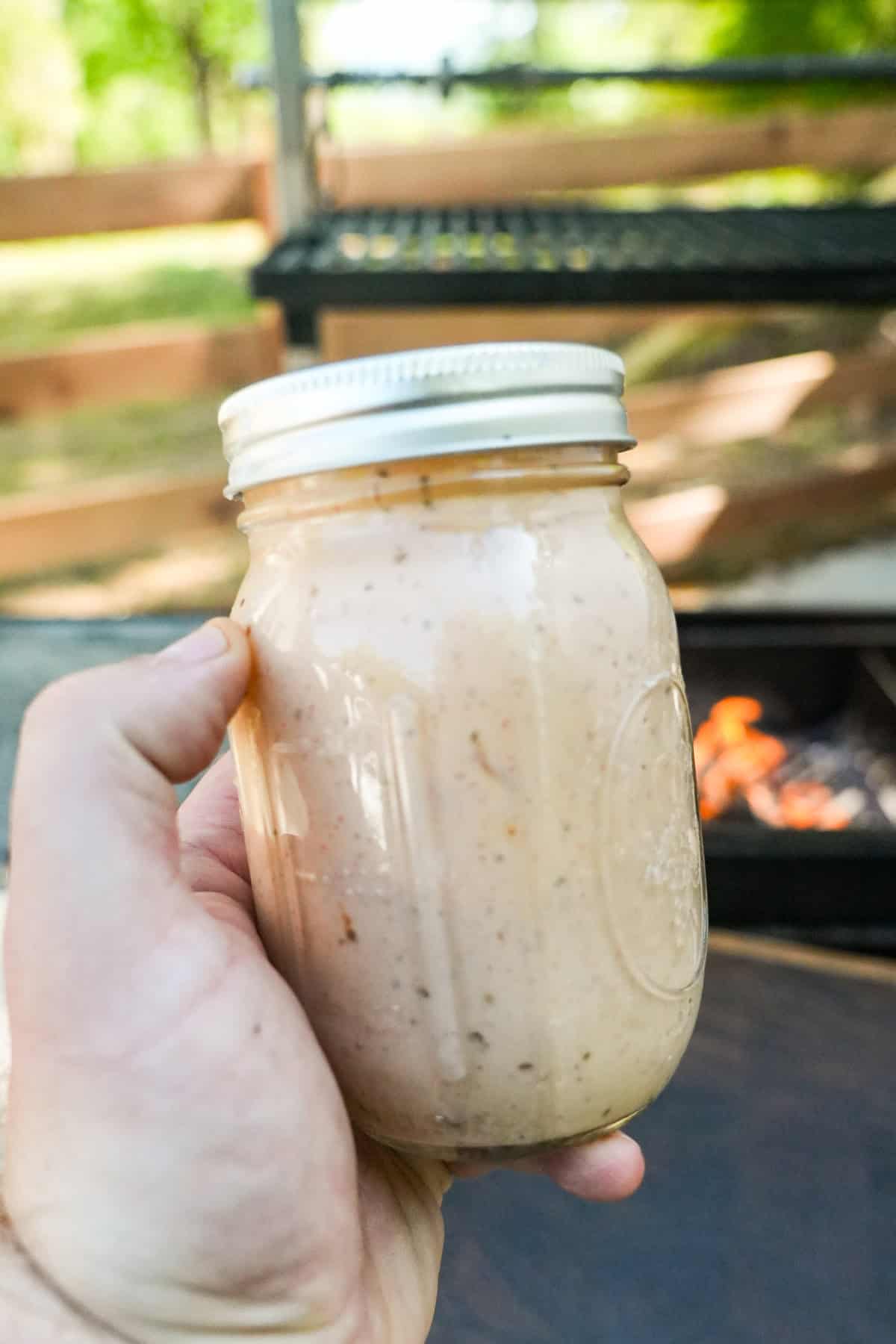 Derek Wolf holding a mason jar filled with honey chipotle yogurt sauce