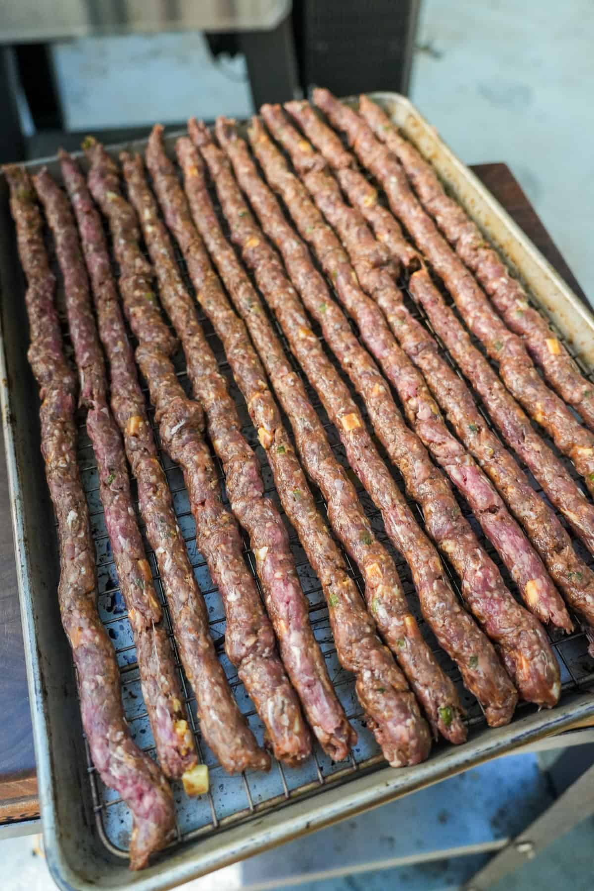 Assembled Texas Twinkie beef sticks lined up on a baking sheet
