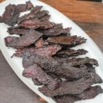 A white platter of finished crispy brisket jerky