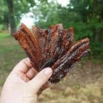 Smoked Bacon Jerky held in a fan fashion.