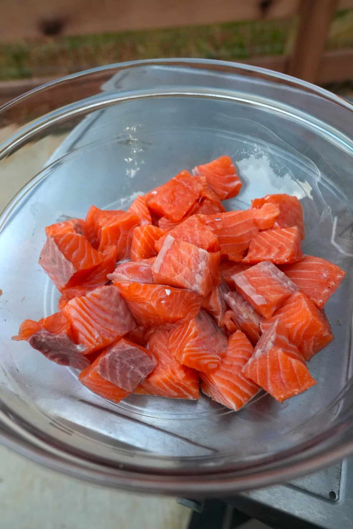 Raw cubes of salmon in a glass bowl