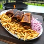 Finished chicken shawarma on a platter with fries and sliced pickled red onions