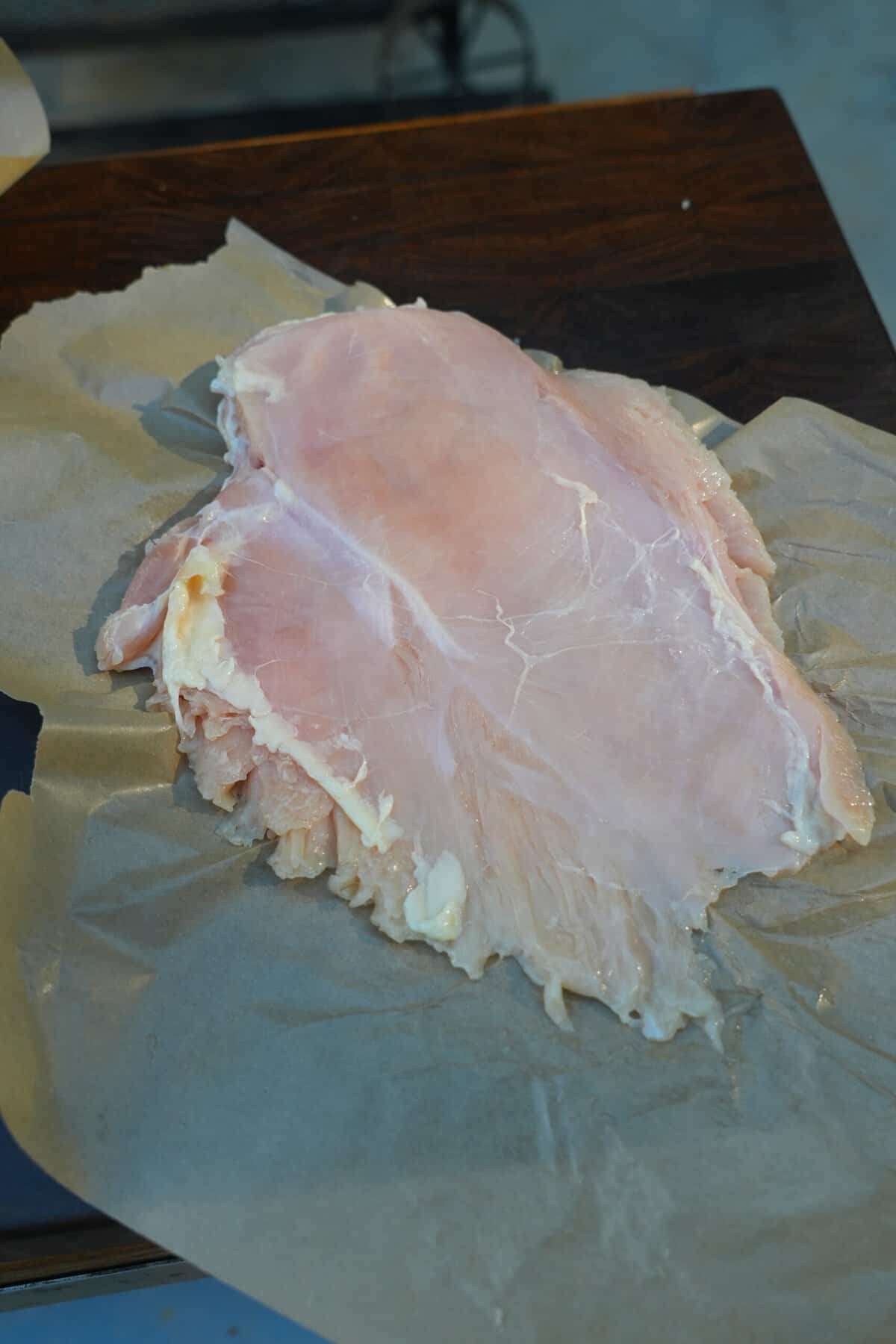 Flattened chicken breasts on parchment paper