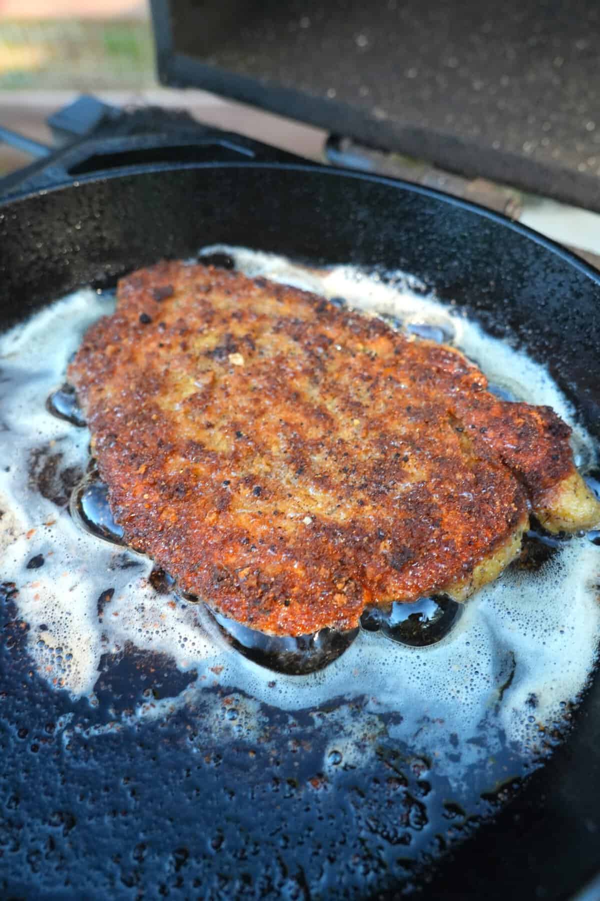 A perfect chicken Parmesan crust in oil in the cast iron skillet