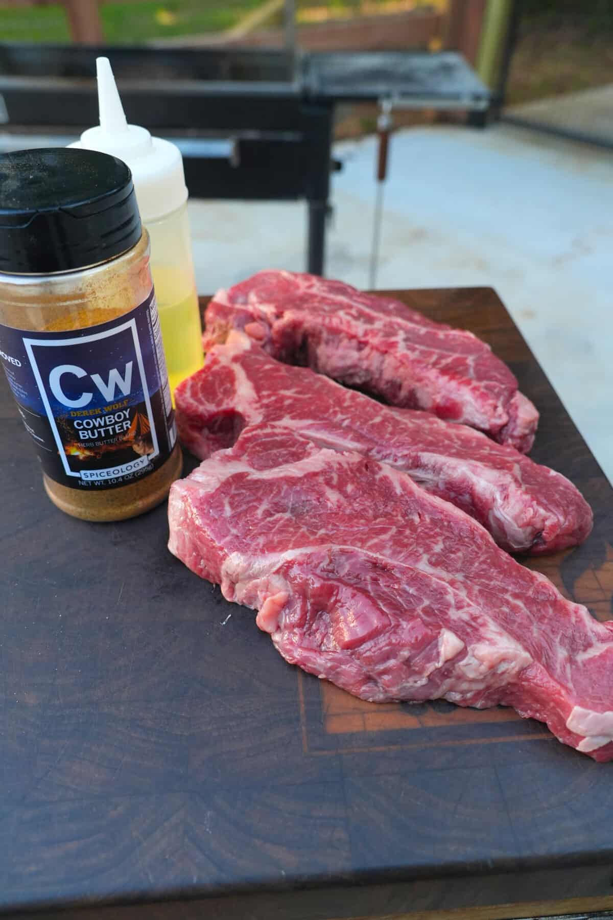 The raw steaks for our steak and truffle fries recipe are lined up next to my favorite Cowboy Butter seasoning.