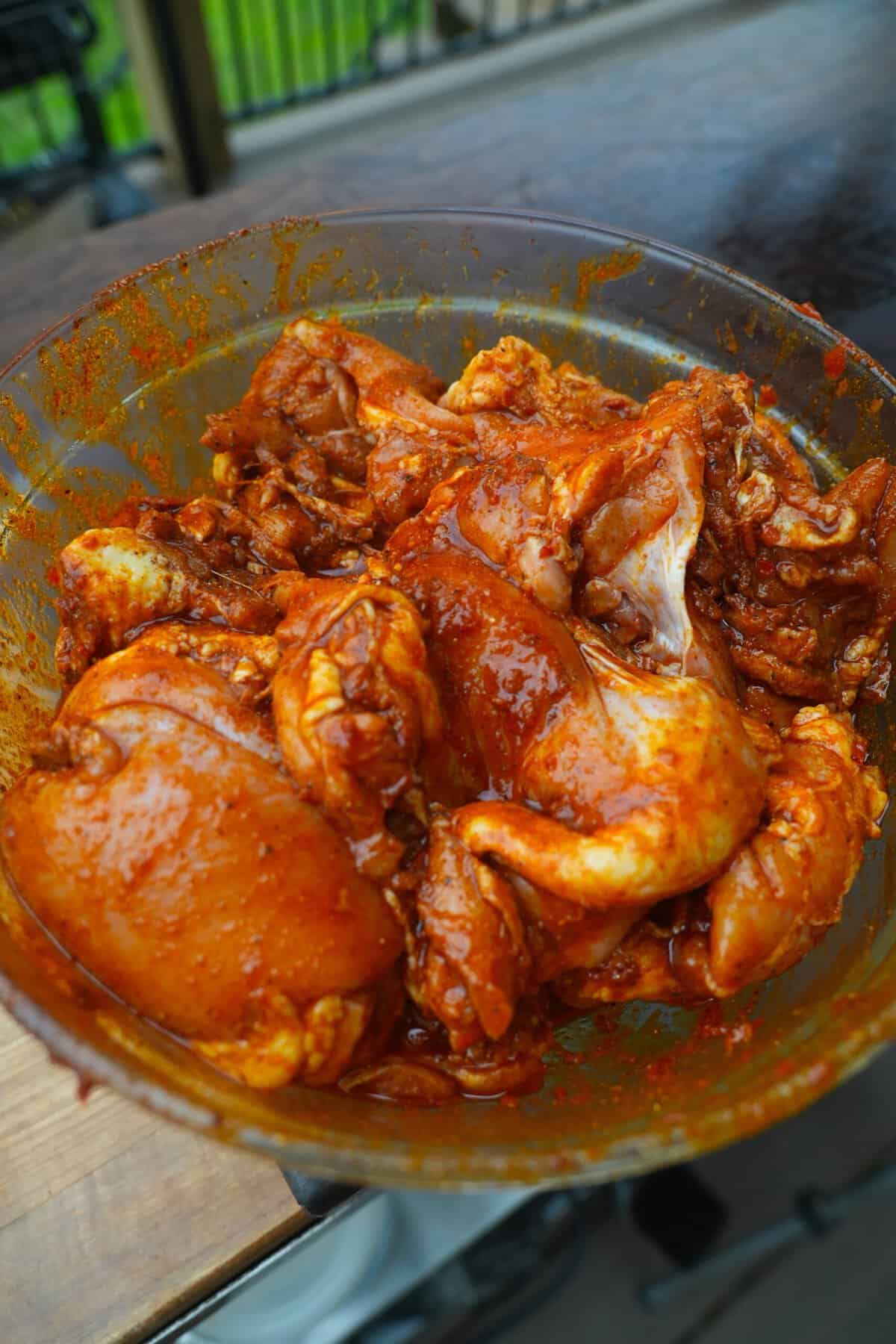 Chicken thighs in a bowl mixed together with shawarma spices for marinating