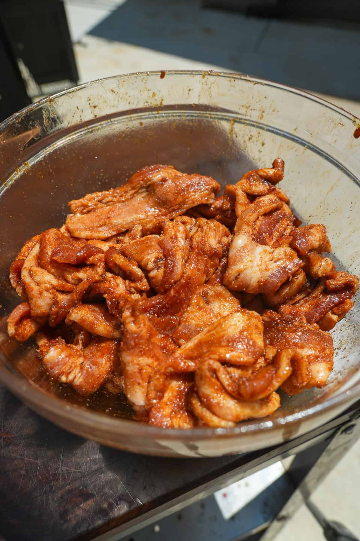 Raw, seasoned bacon in a glass bowl.