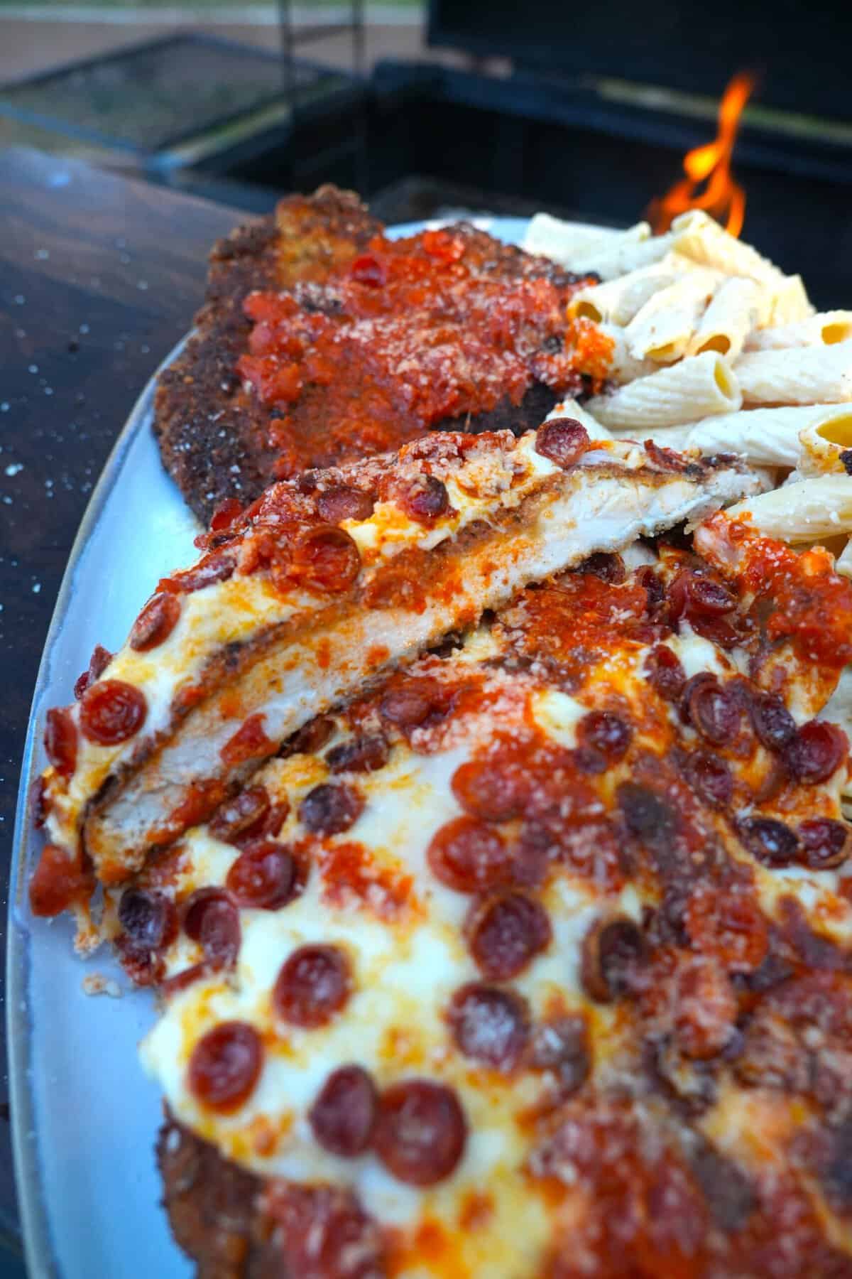 Sliced chicken pizza Parmesan on a plate, with pepperoni, melted cheese and tomato sauce as toppings