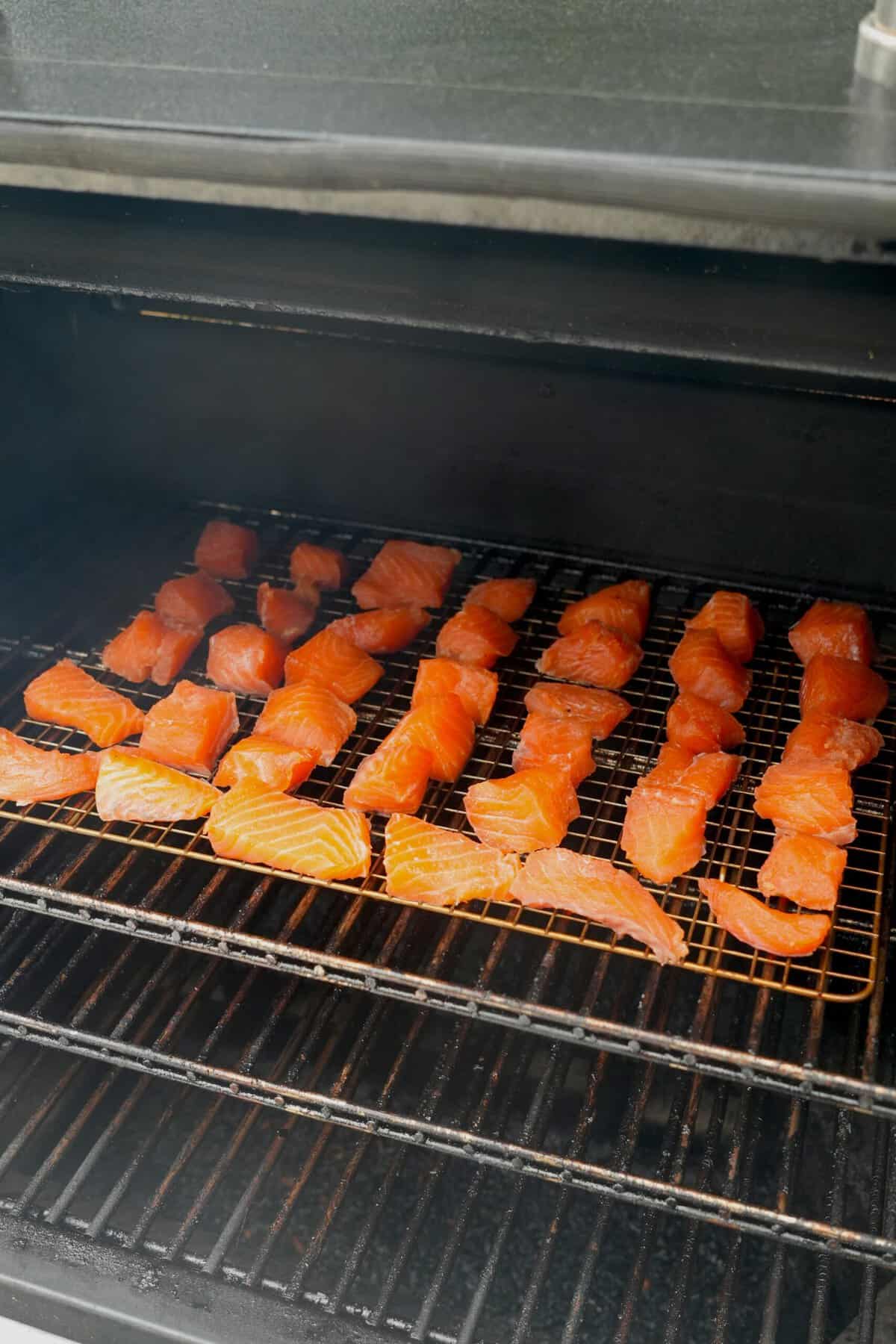 Rows of maple bourbon salmon burnt ends on the smoker