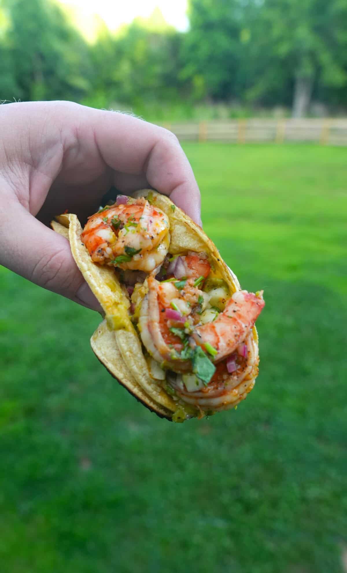 Derek Wolf holding up a finished dirty shrimp taco
