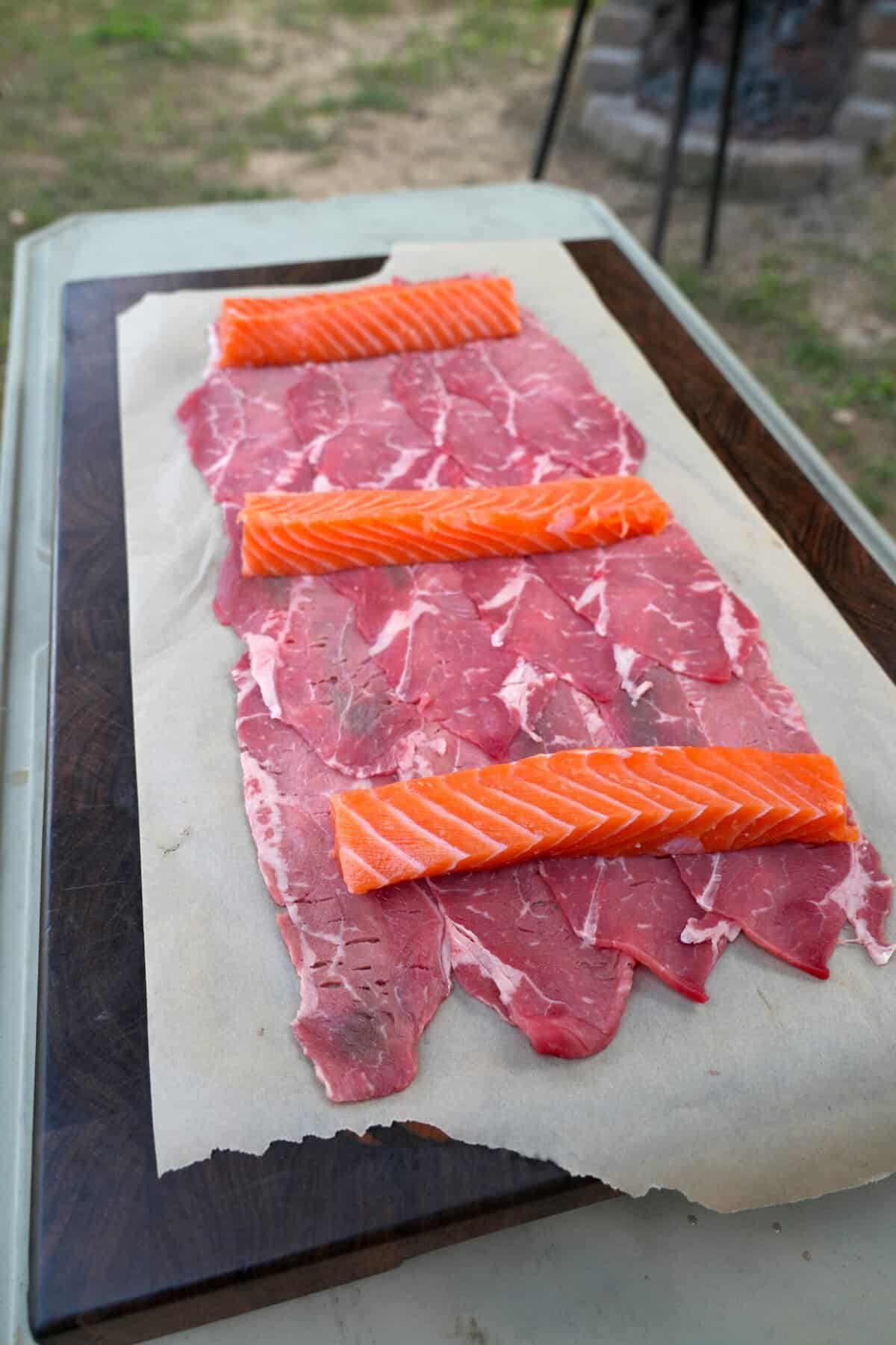 Layering slices of beef and salmon to make beef and salmon skewers