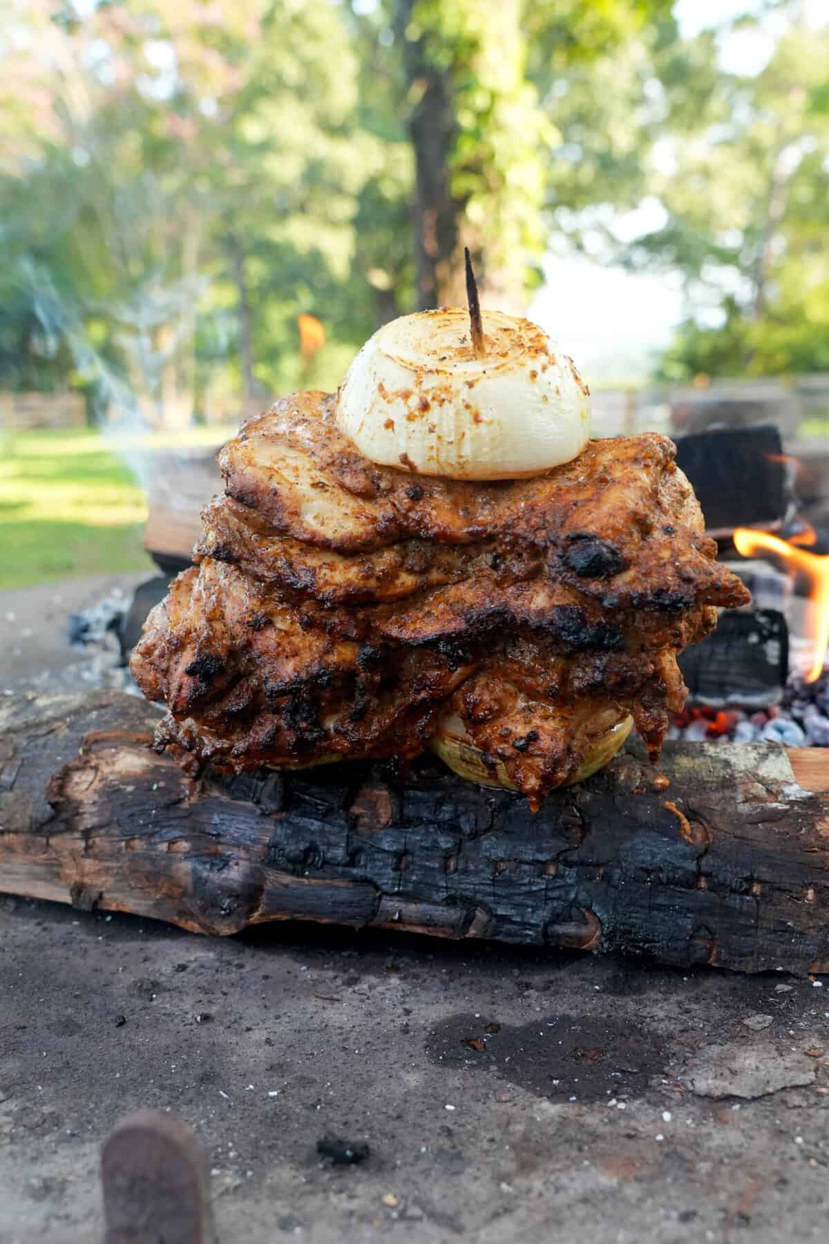 Stacked slices of marinated chicken thighs on skewers with an onion on top