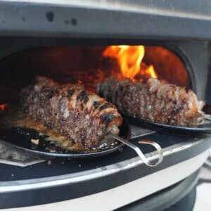 Grilling picanha flake steak skewers over an open flame.