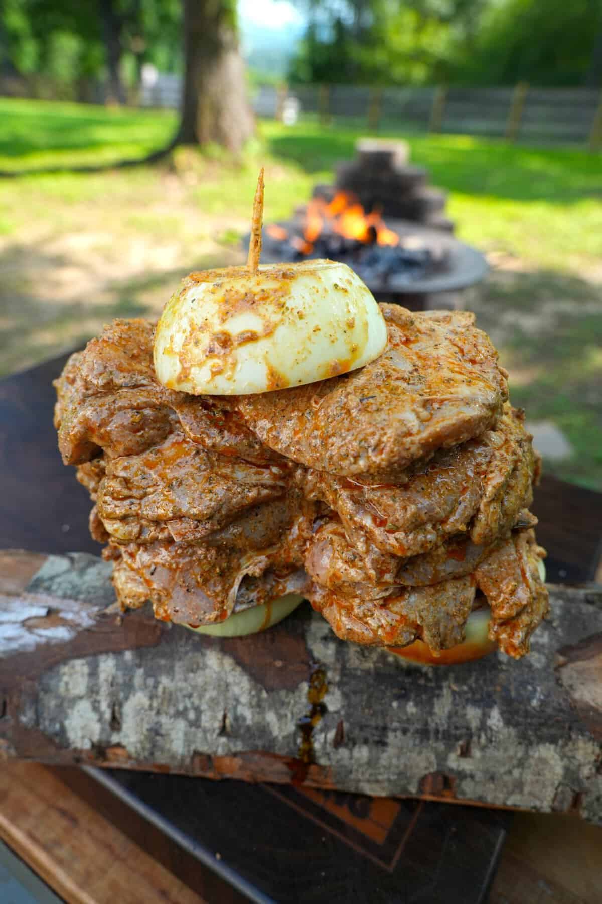 Chicken on skewers with an onion on top, ready to cook on the grill