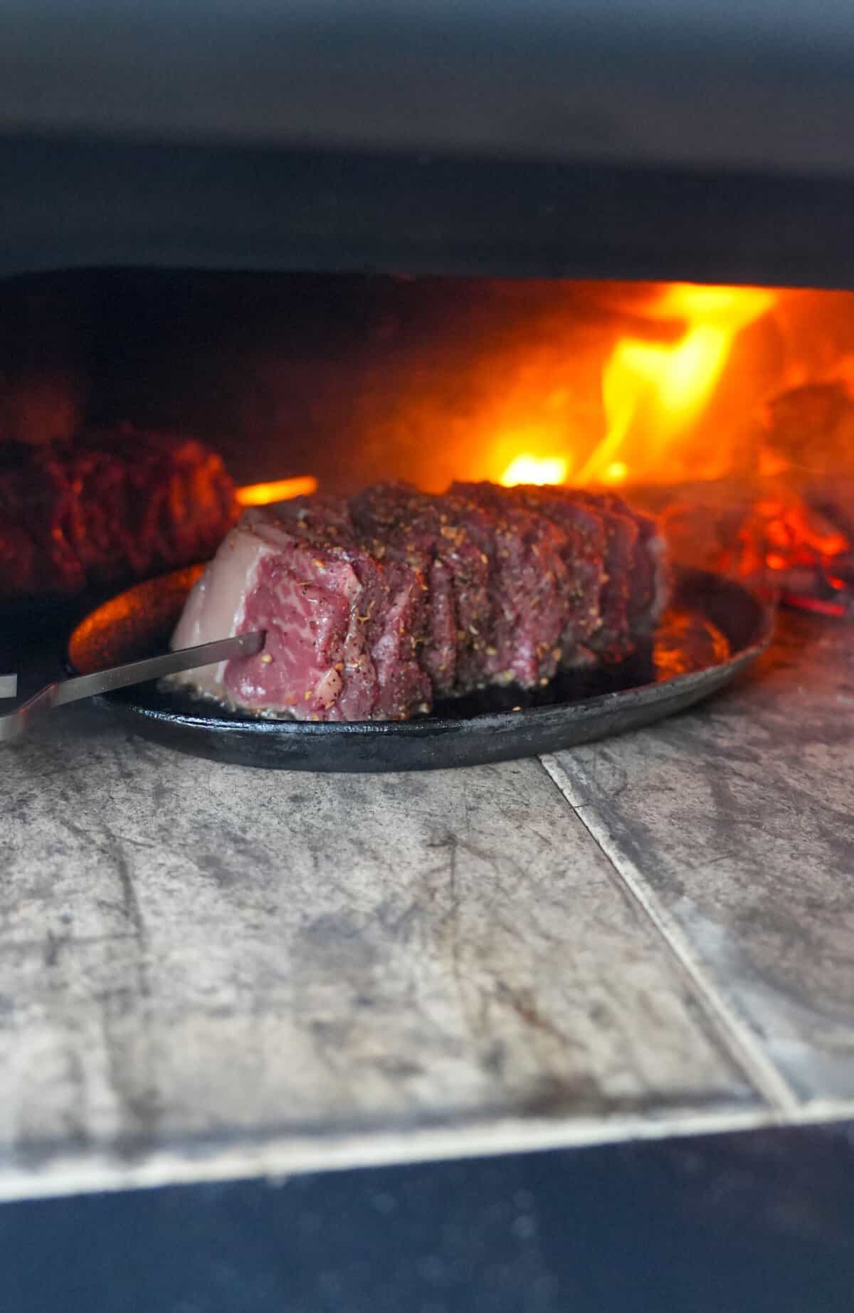 Picanha steak skewers cooking on a grill with open flame.