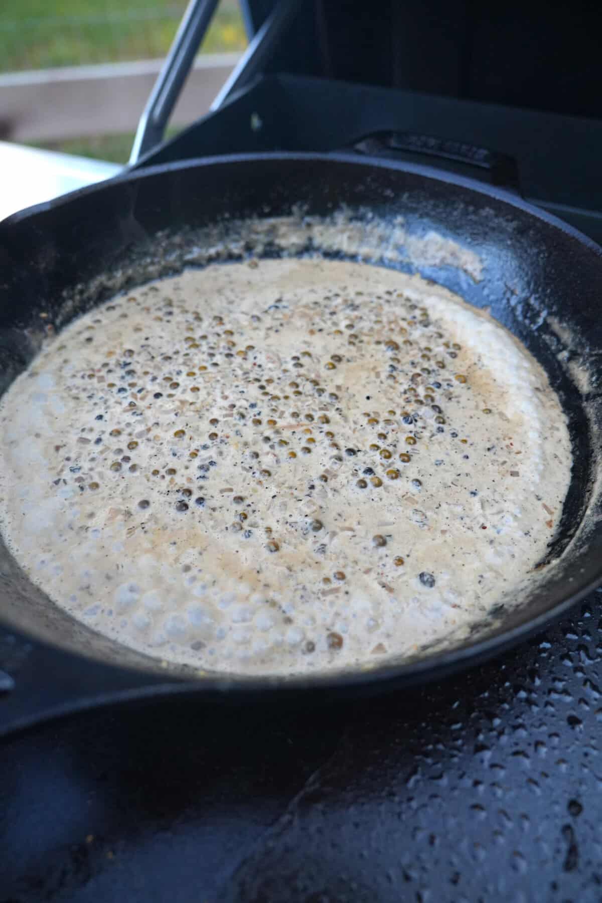 A finished whisky peppercorn cream sauce in a cast iron skillet