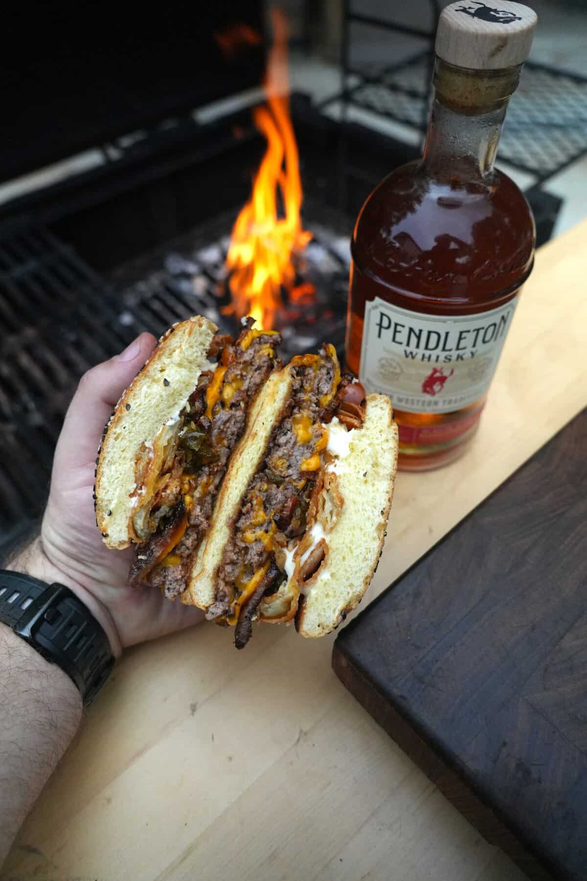 Another shot of the whiskey BBQ hamburger sliced in half next to a bottle of Pendleton Whisky.