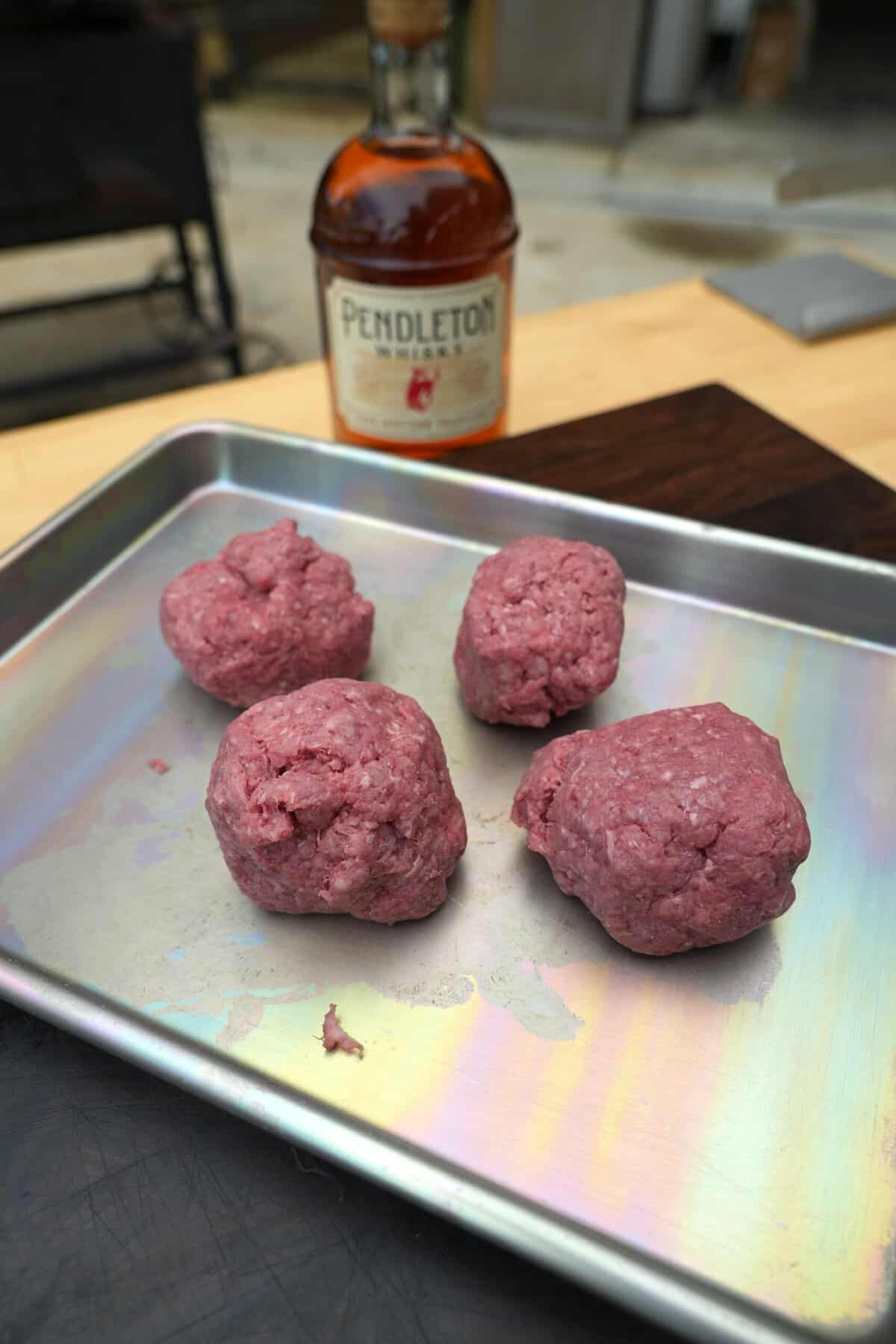 A shot of the high quality beef ready for grilling next to a bottle of the whiskey.