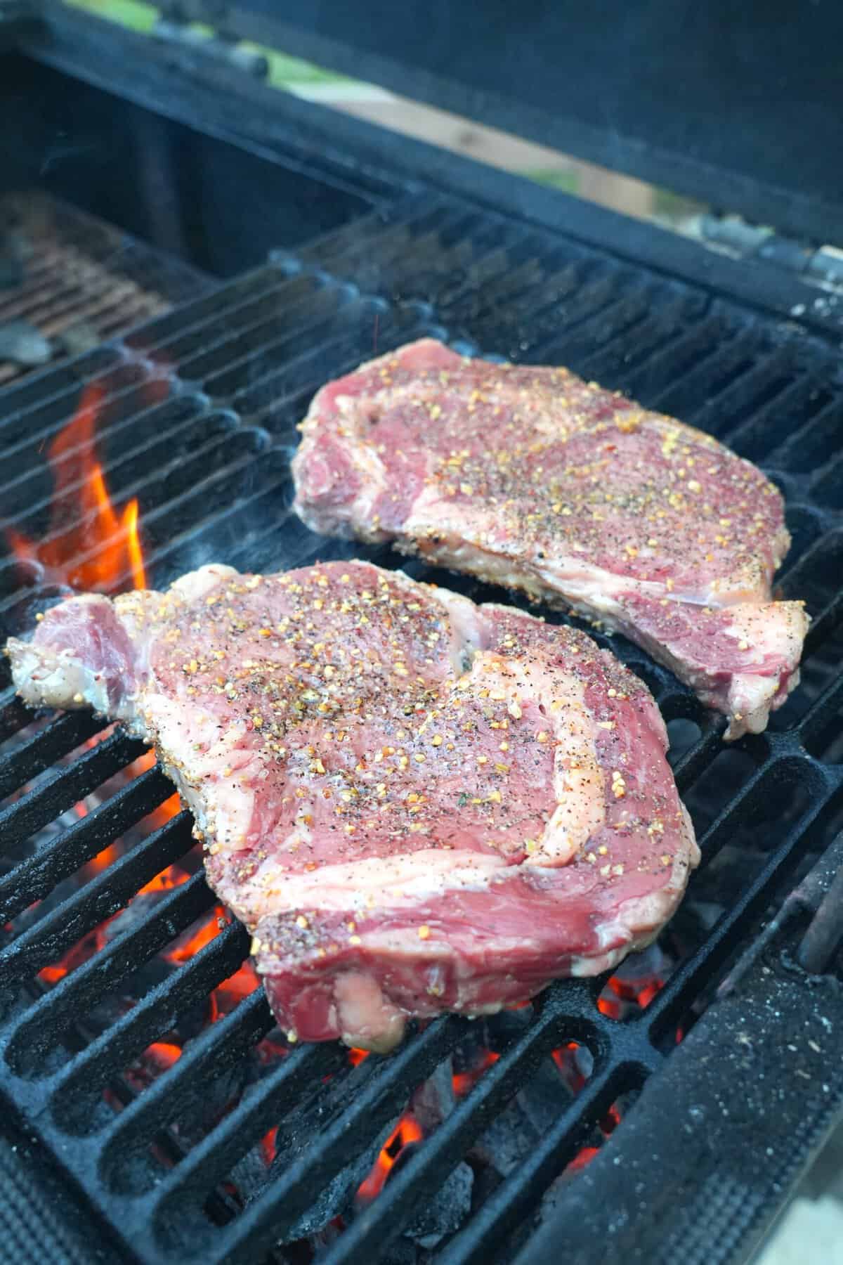 Searing two ribeye steaks on a hot grill