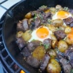 Steak and Eggs with Honey Cajun Butter are sizzling in the cast iron pan over the fired-up grill.