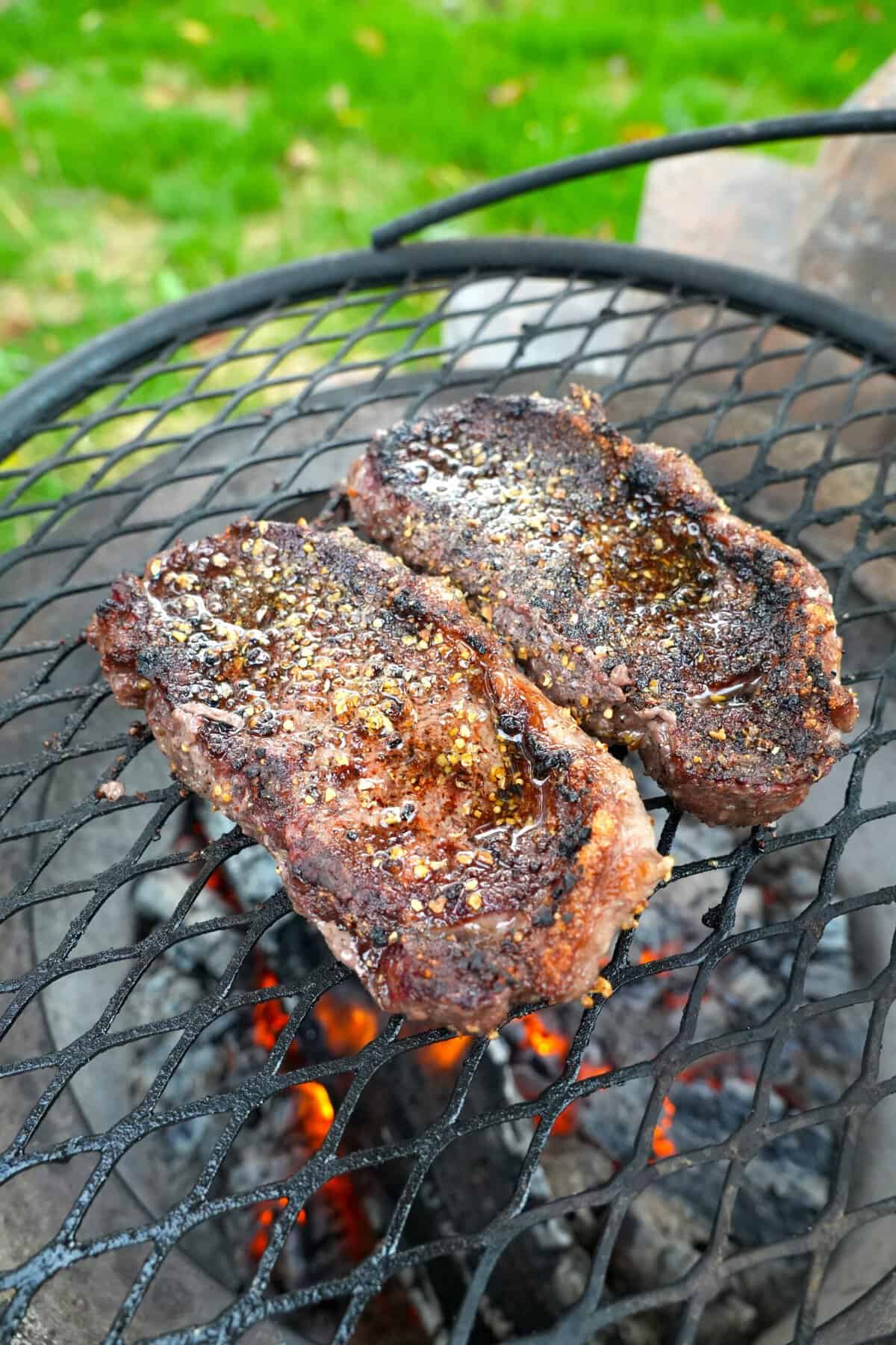 Two cooked steaks over a grill fire
