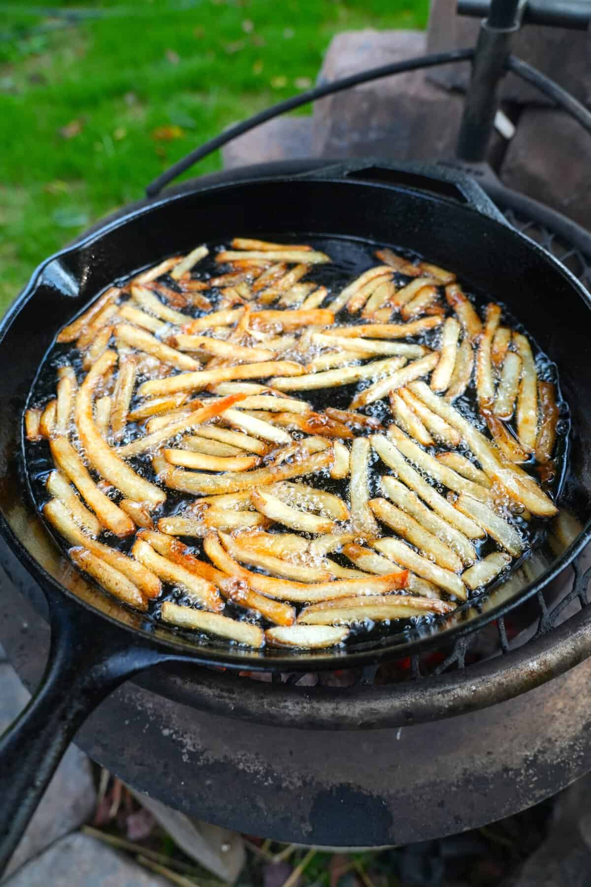 Finished fries in oil in a cast iron pot on the grill