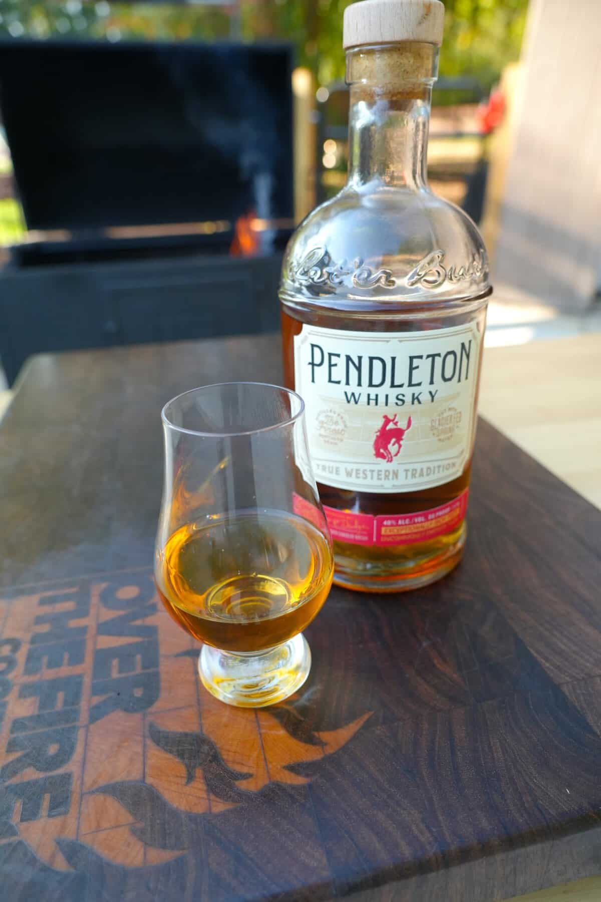 A glass of whisky is poured next to the bottle