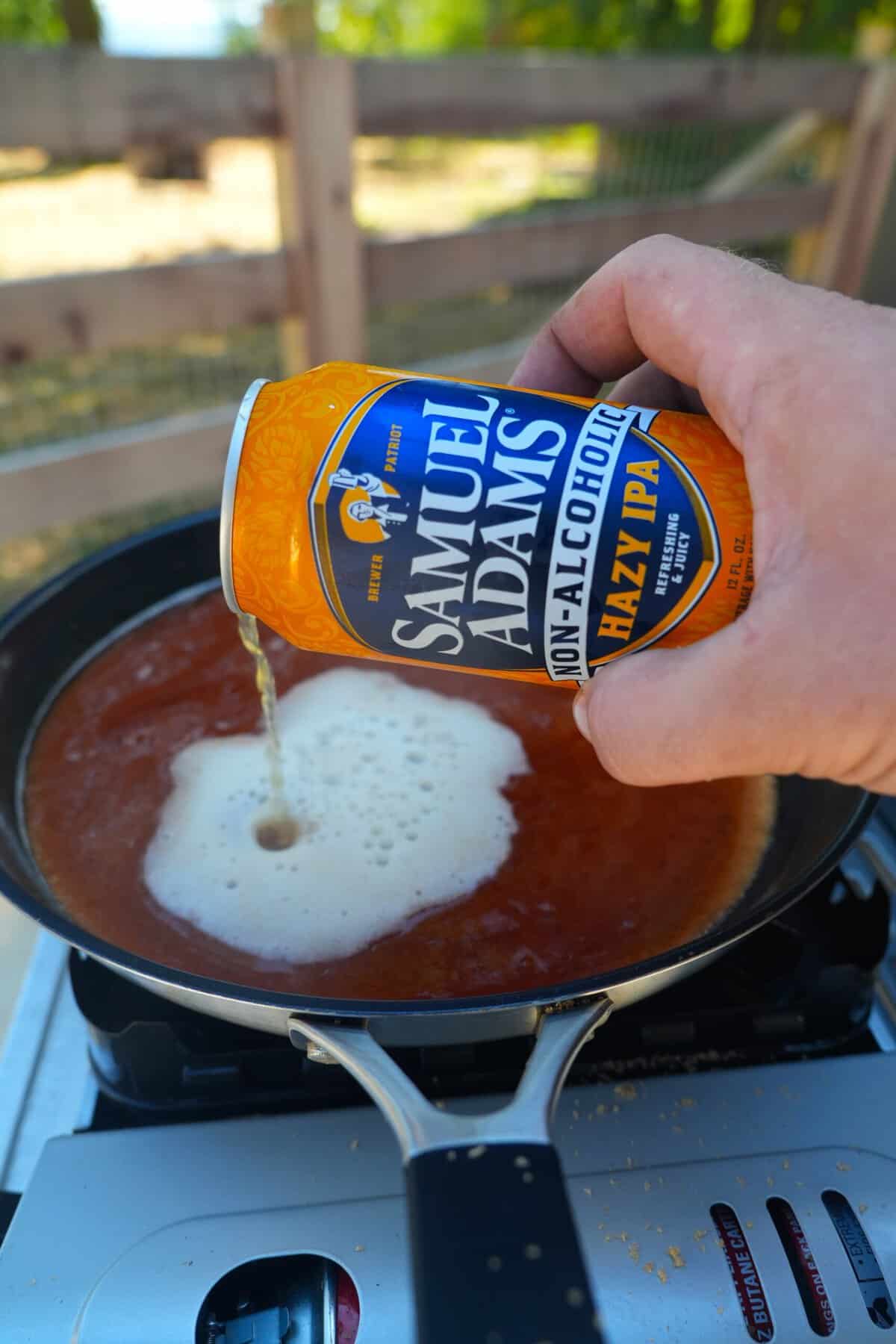 Derek Wolf pouring Samuel Adams Just the Haze IPA into a saucepan with other honey chipotle BBQ sauce ingredients